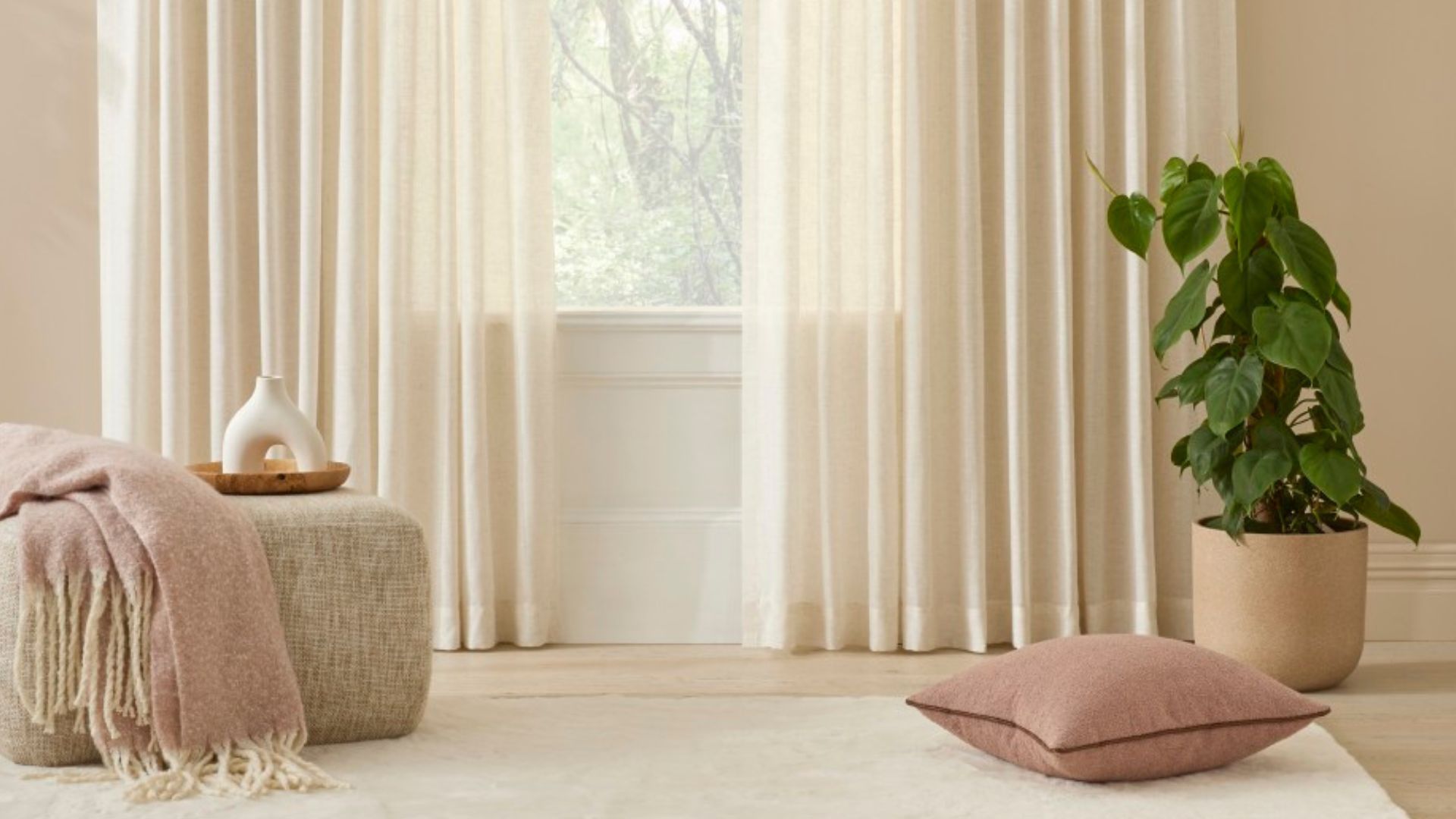 Sheer cream coloured curtains in a warm beige theme room