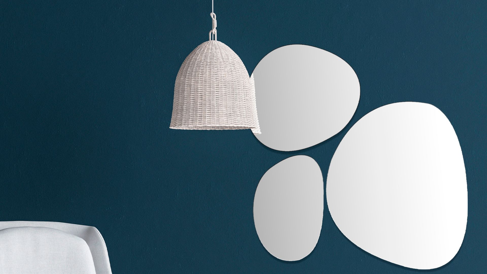 White basket woven lampshade against dark steel blue walls with free-form round mirrors