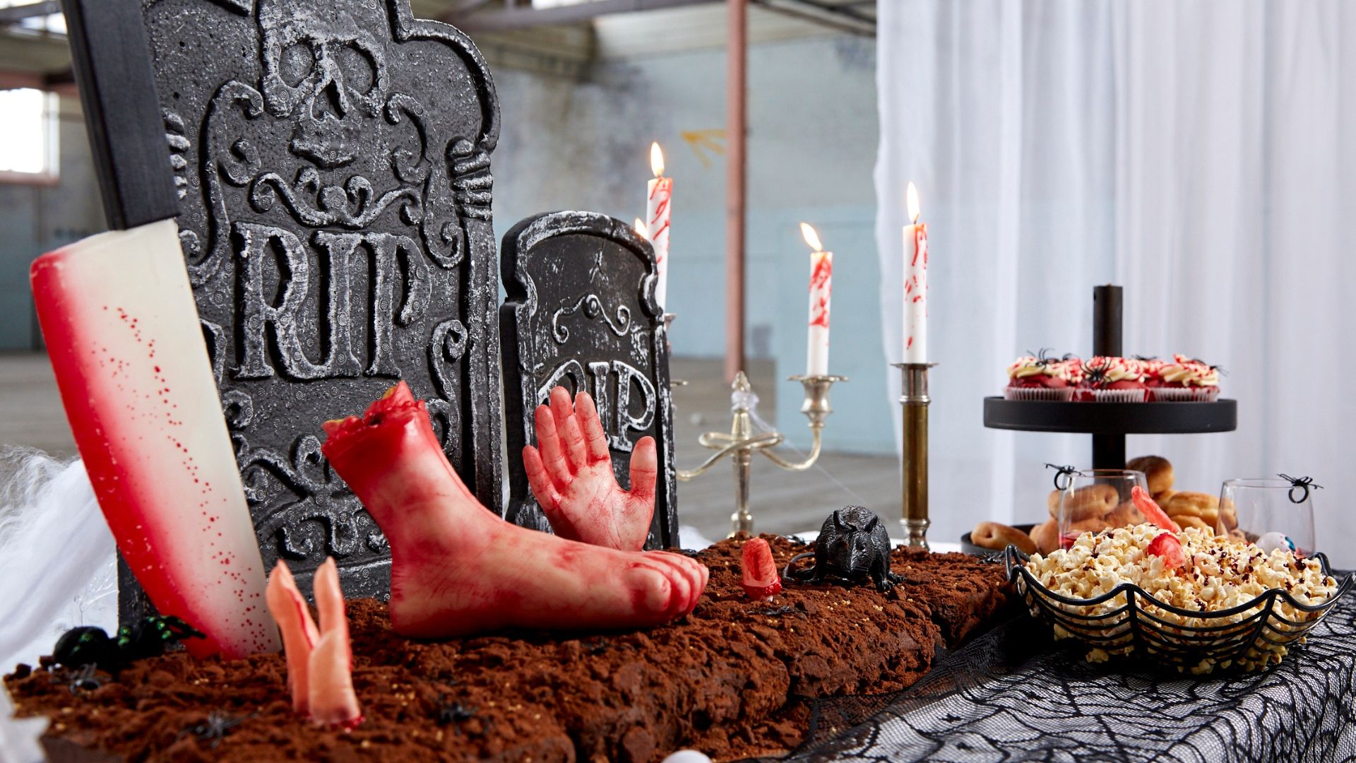 Snack table decorated with fake blood candles, gravestones and zombie hands