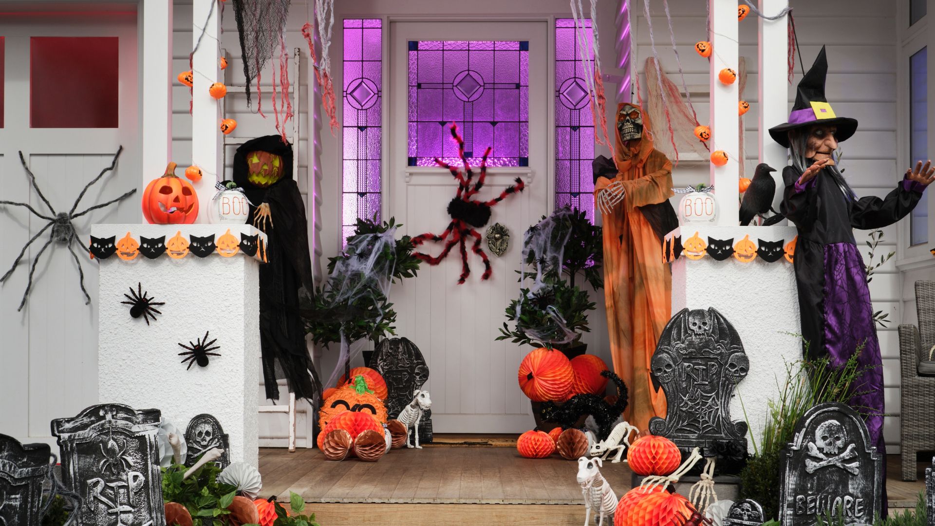 Front porch decorated with pumpkins, spiders, skeletons and gravestone decorations